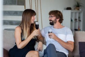 heureux-couple-se-detendre-boire-du-vin-parler-assis-canape-moments-romantiques-maison